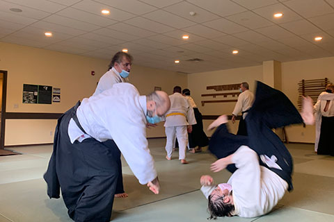 Students practicing aikido techniques in small groups
